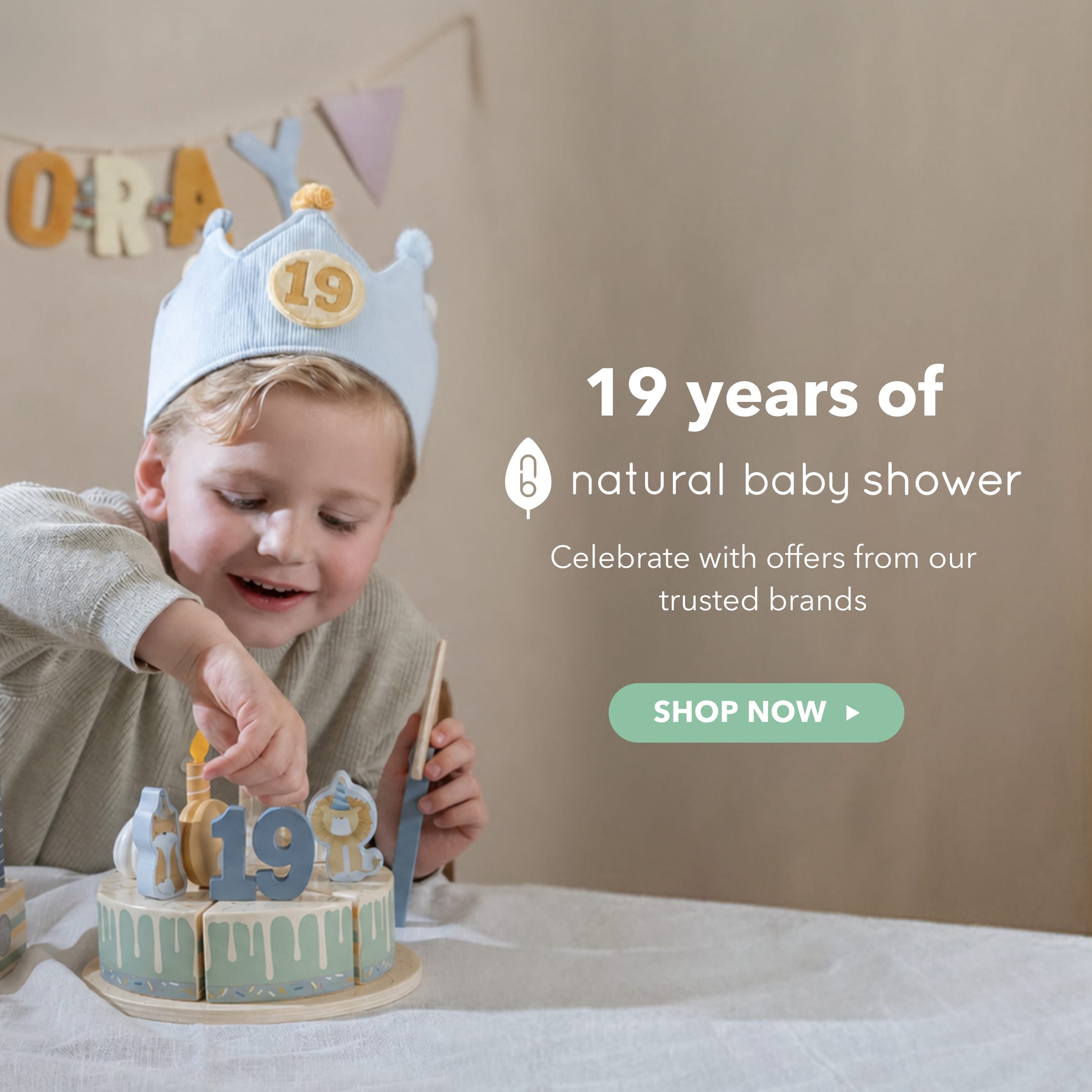 A young child wearing a light blue crown party hat with a gold '19' candle on it, reaching toward a decorated birthday cake with '19' candles. The scene includes promotional text reading '19 years of natural baby shower' and a 'SHOP NOW' button on a beige background.